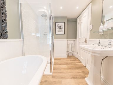 A bathroom with a bathtub shower enclosure pedestal sink and a door at Prospect House Ambleside