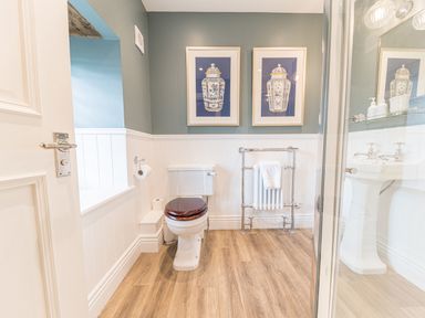 A bathroom with a toilet a towel rack and framed pictures on the wall at Prospect House in Ambleside