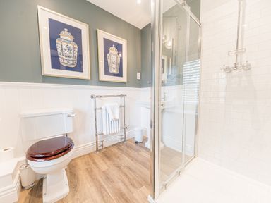 A bathroom with a toilet a towel rack a sink and a glass shower enclosure at Prospect House in Ambleside