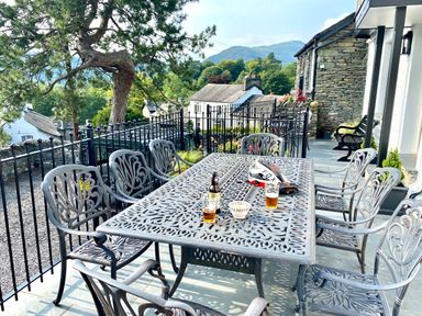 An outdoor patio with a metal table and eight chairs with drinks and a bowl on the table at Prospect House in Ambleside