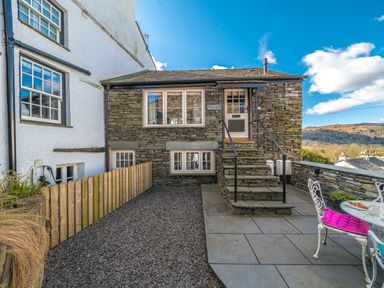 An outdoor patio with stone stairs leading to a door and a small table with chairs at Prospect Cottage Loft in Ambleside
