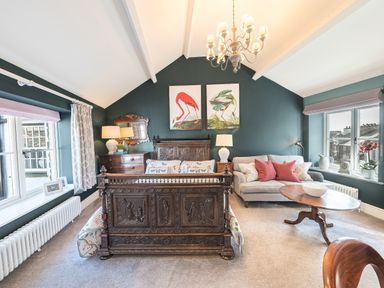 A bedroom with carved wooden bed chest of drawers sofa and coffee table at Prospect Cottage Loft in Ambleside