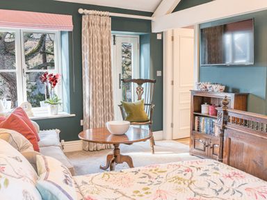 A living room with a wooden chair cushion table bookshelf and wall mounted television at Prospect Cottage Loft in Ambleside