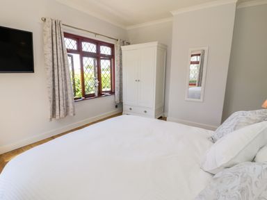 A bedroom with a bed pillows wardrobe mirror window and wall mounted tv at Berwyn in Talybont
