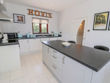 A kitchen with white cabinets black countertops a kitchen island and wall decorations at Berwyn in Talybont