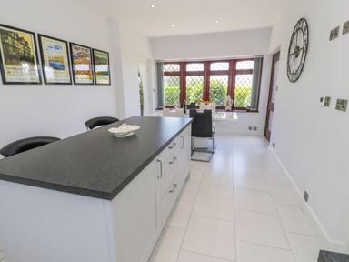 A kitchen with an island counter and dining table near windows at Berwyn in Talybont