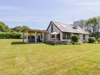 A house with a large lawn a covered outdoor seating area and patio furniture at Berwyn in Talybont