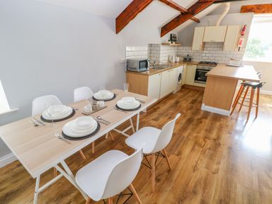 A kitchen and dining area with a wooden floor and white cabinets at The Old Brewery in Saundersfoot