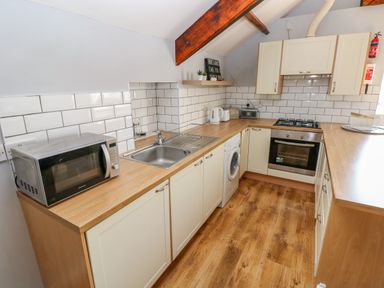 A kitchen with microwave washing machine oven and sink at The Old Brewery in Saundersfoot