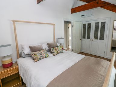 A bedroom with a bed a bedside table with a lamp and wooden ceiling beams at The Old Brewery in Saundersfoot