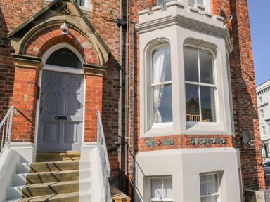 An entrance door with steps and a bay window on a brick building at 1 Church Square in Whitby
