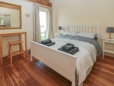 A bedroom with a white bed and bedside tables with lamps at The Long Barn in Berwick-Upon-Tweed
