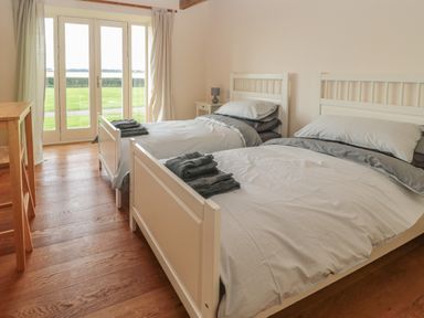 A bedroom with two single beds and folded towels on each bed at The Long Barn in Berwick-Upon-Tweed