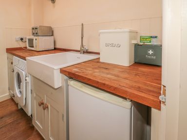 A kitchen counter with a white sink toaster microwave bread box and first aid kit at The Long Barn in Berwick-Upon-Tweed
