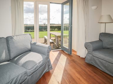 A living room with two sofas wooden floor and a door opening to a garden with a picnic table at The Long Barn in Berwick-Upon-Tweed