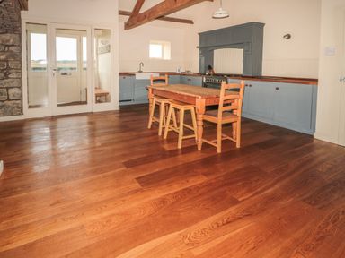 A kitchen with wooden dining table and chairs and blue cabinets at The Long Barn in Berwick-Upon-Tweed