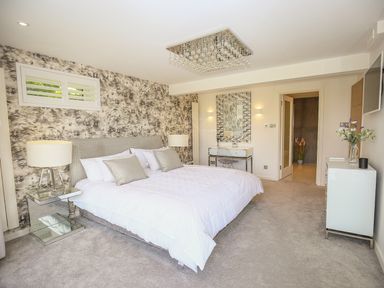 A bedroom with a bed two bedside tables a wall mirror and a dresser at Shutts House Garden Apartment in Coombe Bissett