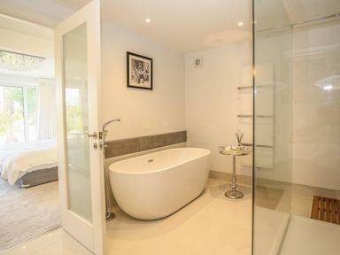 A bathroom with a freestanding bathtub small table and glass shower enclosure at Shutts House Garden Apartment in Coombe Bissett
