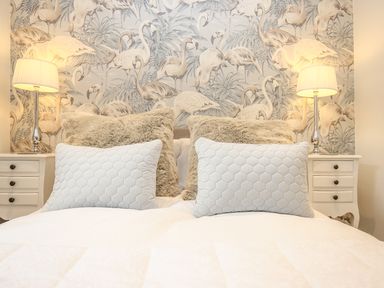A bed with white and beige pillows and two bedside tables with lamps in a bedroom at Shutts House Garden Apartment in Coombe Bissett
