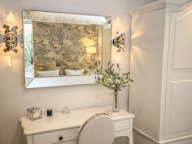 A dressing table with a mirror flowers and decorative items in a bedroom at Shutts House Garden Apartment in Coombe Bissett