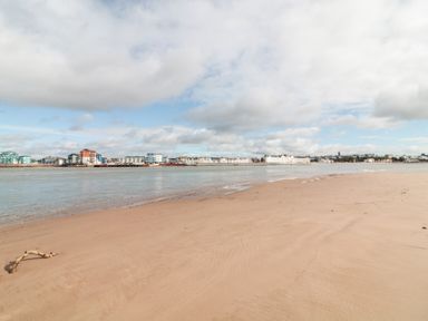 A sandy beach with water and buildings along the shoreline at Sea Point in Exmouth