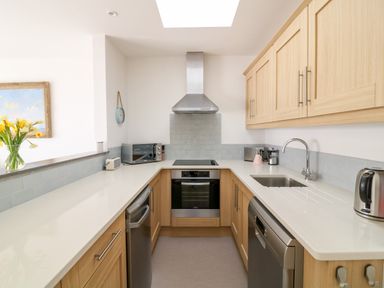 A kitchen with wooden cabinets stainless steel appliances a sink and a vase of yellow flowers at Sea Point in Exmouth