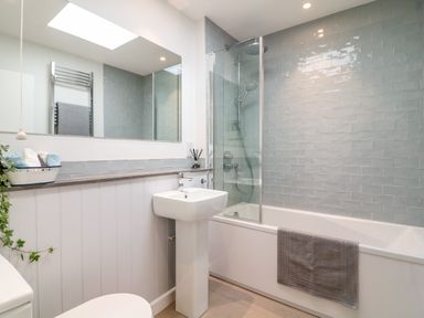 A bathroom with a bathtub and shower next to a sink and mirror at Sea Point in Exmouth