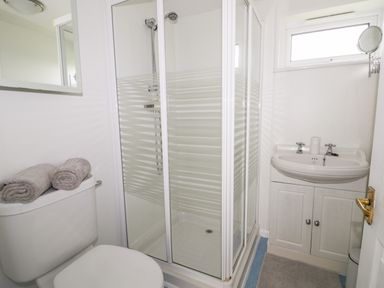 A bathroom with a shower enclosure toilet with towels and a sink with cabinet at Thirley Beck Lodge in Harwood Dale