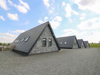 Four stone cottages with steep pitched roofs on a gravel ground under a partly cloudy sky at Elan Valley Welsh - The Sheepfold in Llanyre near Llandrindod Wells