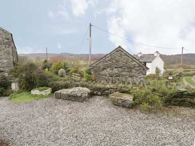 A gravel yard with stone walls and buildings surrounded by bushes and hills at Rusland View Rusland near Newby Bridge