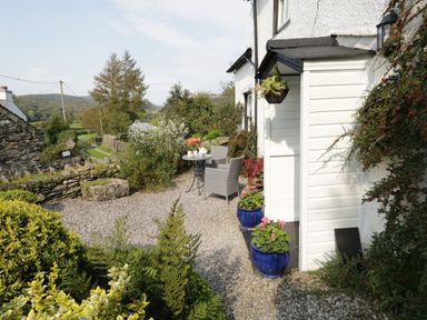 An outdoor seating area with a small table and chairs surrounded by plants and gravel at Rusland View Rusland near Newby Bridge