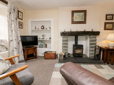 A living room with a fireplace television books and seating at Rusland View Rusland near Newby Bridge