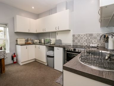 A kitchen with white cabinets a stove a microwave a toaster and a sink at Rusland View Rusland near Newby Bridge