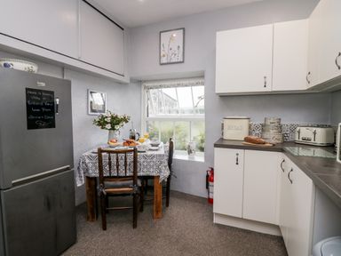 A kitchen with a dining table set for breakfast a refrigerator cabinets and a bread box at Rusland View Rusland near Newby Bridge