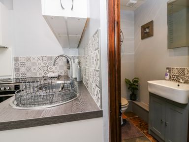 A kitchen sink with a dish rack and patterned tiles next to a small bathroom with a sink and toilet at Rusland View Rusland near Newby Bridge