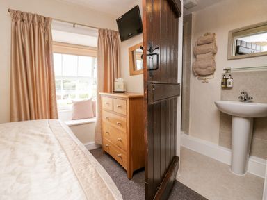 A bedroom with a bed dresser and window connected to a bathroom with a sink at Rusland View Rusland near Newby Bridge