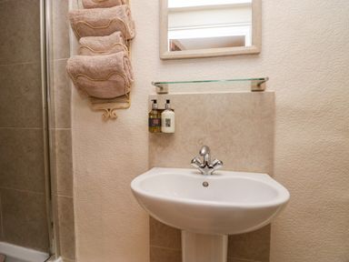 A bathroom sink with two soap dispensers a mirror and folded towels on a wall rack at Rusland View Rusland near Newby Bridge