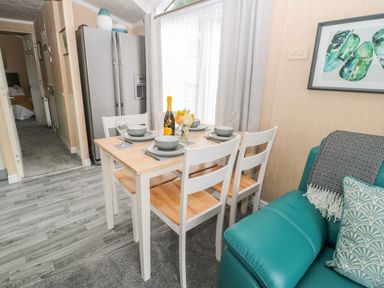 A dining area with a wooden table set for four near a teal sofa and a stainless steel refrigerator at Ramblers Rest in Felton