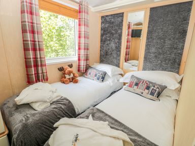 A bedroom with two single beds pillows and blankets a window with red plaid curtains and a stuffed moose toy at Ramblers Rest in Felton