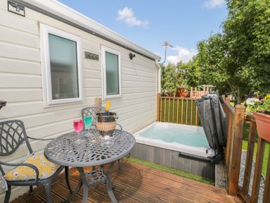 A deck with a metal table and two chairs next to a hot tub outside a mobile home at Ramblers Rest in Felton