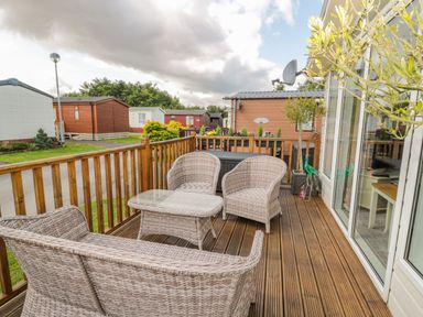 An outdoor wooden deck with wicker chairs a glass-top table and a wooden railing at Ramblers Rest in Felton