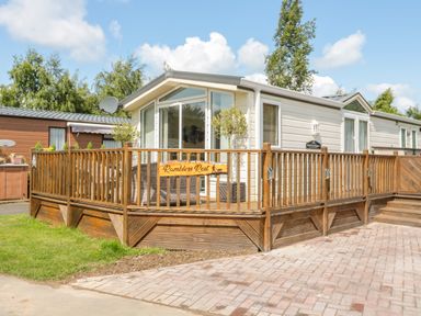 A single story mobile home with wooden deck and outdoor seating at Ramblers Rest in Felton