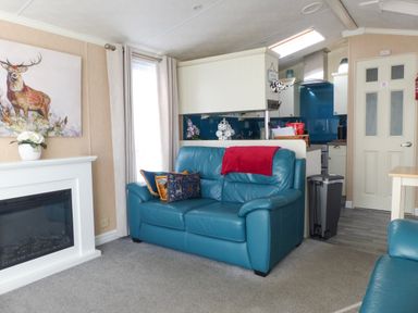 A living room with a blue leather sofa cushions fireplace and partial kitchen view at Ramblers Rest in Felton
