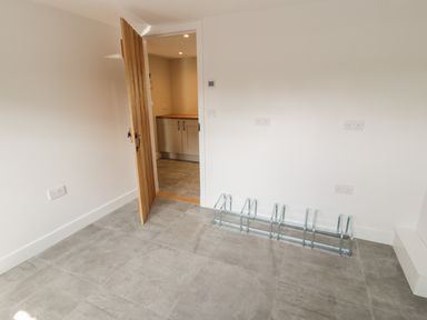 A room with tiled flooring and a wooden door leading to a kitchen with cabinets at Tyn Ffynnon in Dyffryn Ardudwy