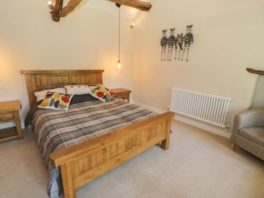 A bedroom with a wooden bed frame and plaid bedding at Tyn Ffynnon in Dyffryn Ardudwy