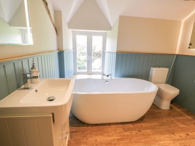 A bathroom with a sink a bathtub a toilet and a window at Tyn Ffynnon in Dyffryn Ardudwy