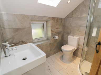 A bathroom with a sink, toilet, shower, and window at Tyn Ffynnon in Dyffryn Ardudwy