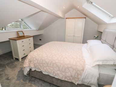 A bedroom with a bed a chest of drawers and a wardrobe at Argraig in Llanbedrog