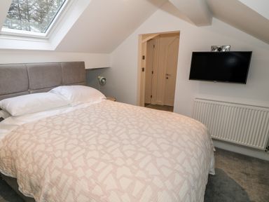 A bedroom with a bed a window a wall-mounted television and a radiator at Argraig in Llanbedrog