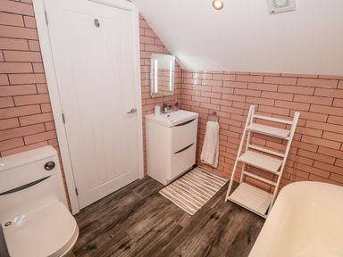 A bathroom with a toilet sink mirror towel rack and bathtub at Argraig in Llanbedrog